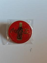 可口可樂奧運限量版徽章，紅色圓形設計，金色瓶身圖案，全新未拆封，帶原裝保護袋。1996年亞特蘭大奧運會限定款，收藏價值高